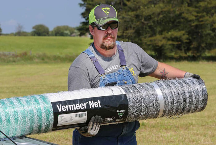 A man holding a roll of netwrap with the label Vermeer Netwrap